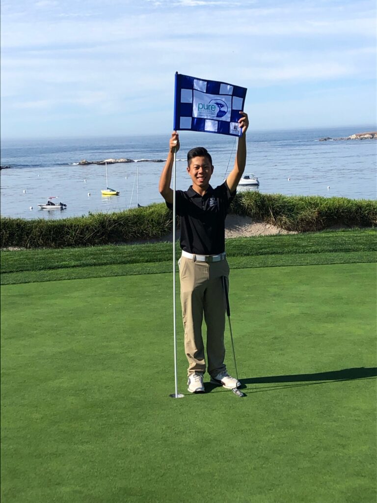 young man smiling having fun on an affordable golf course holding flag by ocean